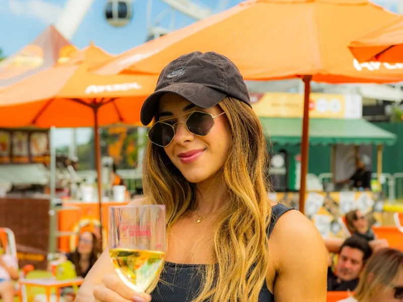 Visitante com taça na área gastronômica do festival